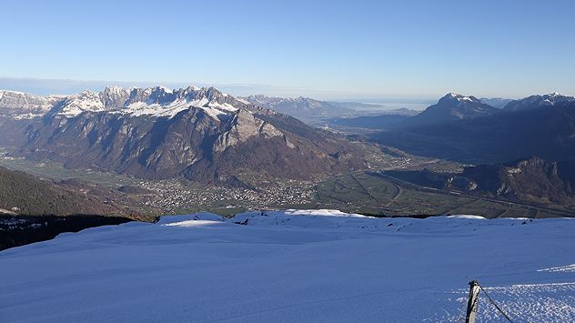 Panorama vom Pizol mit verschneitem Vordergrund und markanter Gebirgskette über dem Rheintal bei klarer Sicht.