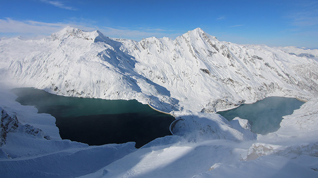 Blauer Himmel und eine tief verschneite Landschaft: Am unteren Bildrand sind Schneeverwehungen der vergangenen Tage zu sehen.