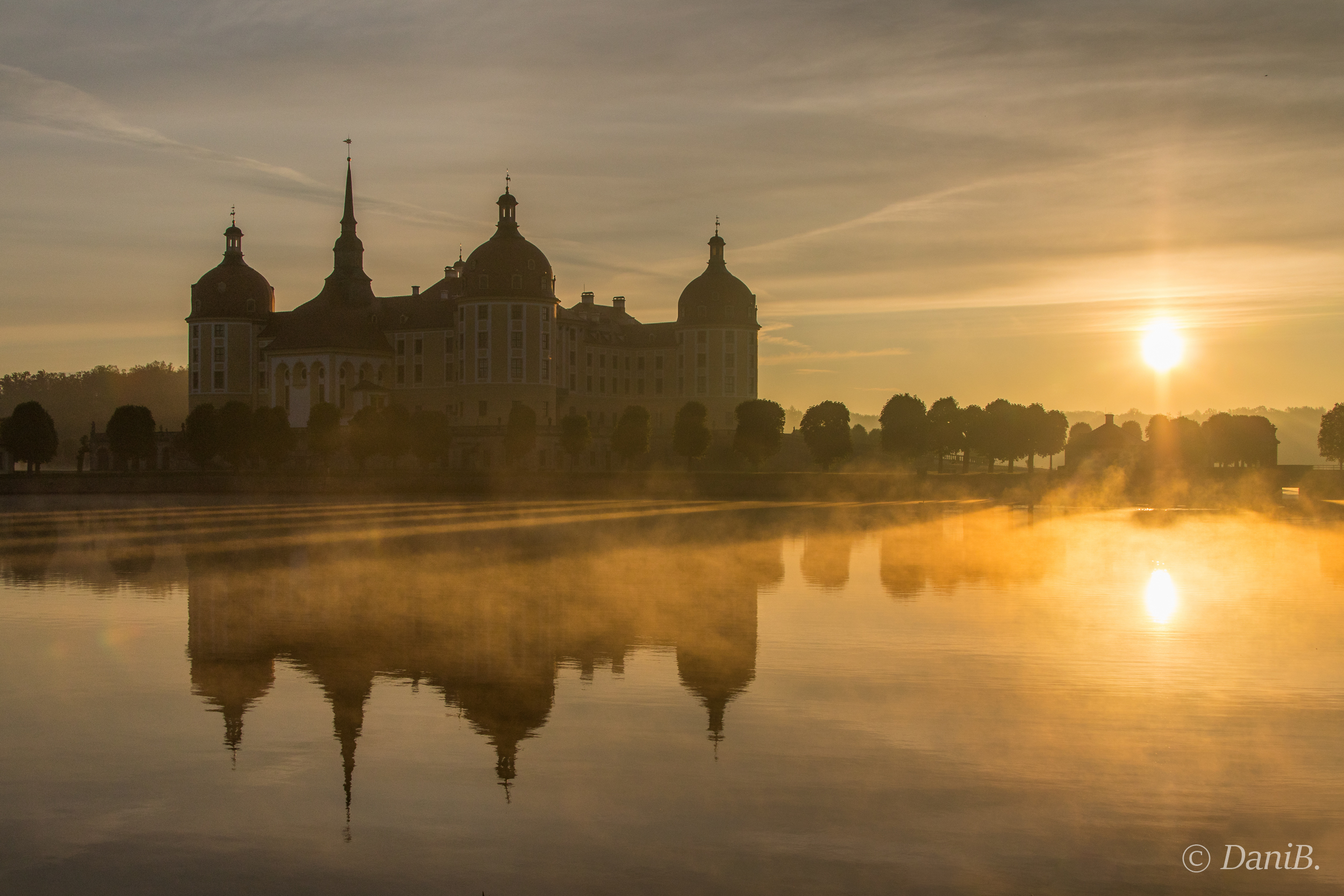 Die Sonne spiegelt sich im früh morgens im Schlossteich, der das Schloss umgibt. 