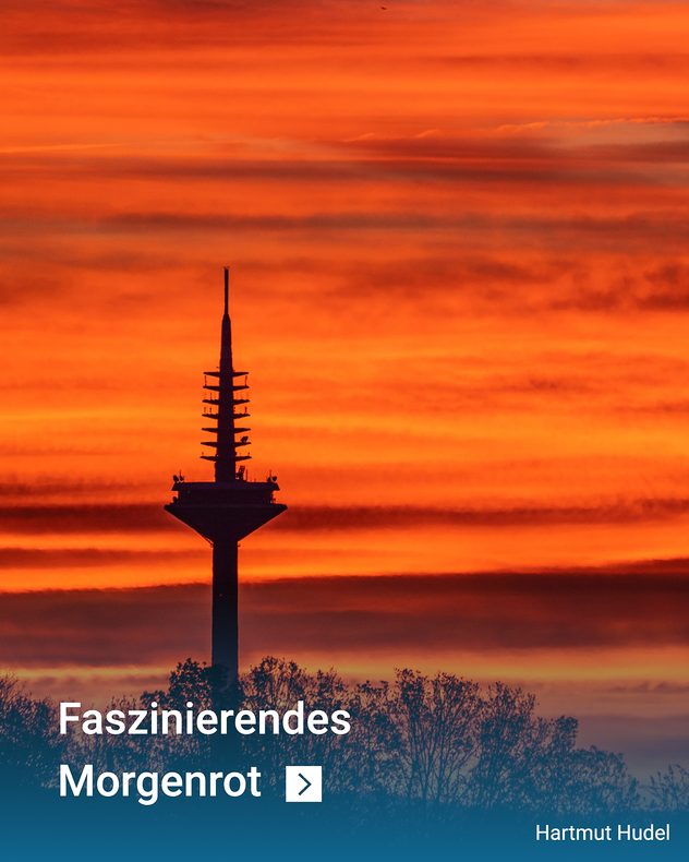 Fernsehturm vor orange-rotem Sonnenaufgang mit leuchtenden Wolken und Baum-Silhouetten.