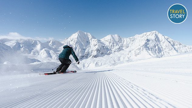 Ein Skifahrer fährt auf einer frisch präparierten Piste, im Hintergrund schneebedeckte Berge. (c) IDM SÃ¼dtirol / Thomas Monsorno