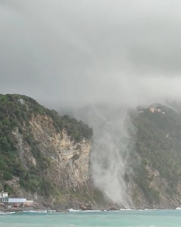 Tromba marina sobre el mar cerca de la costa bajo nubes oscuras.