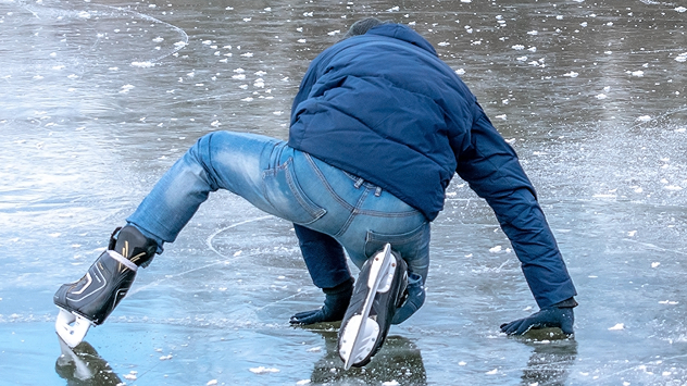 Schlittschuhläufer rutscht auf Eisfläche aus