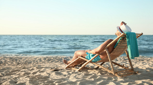 Ein Mann liegt am Strand im Liegestuhl