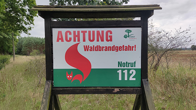 Schild mit Hinweis "Achtung Waldbrandgefahr" und der Aufforderung, den Notruf 112 zu wählen