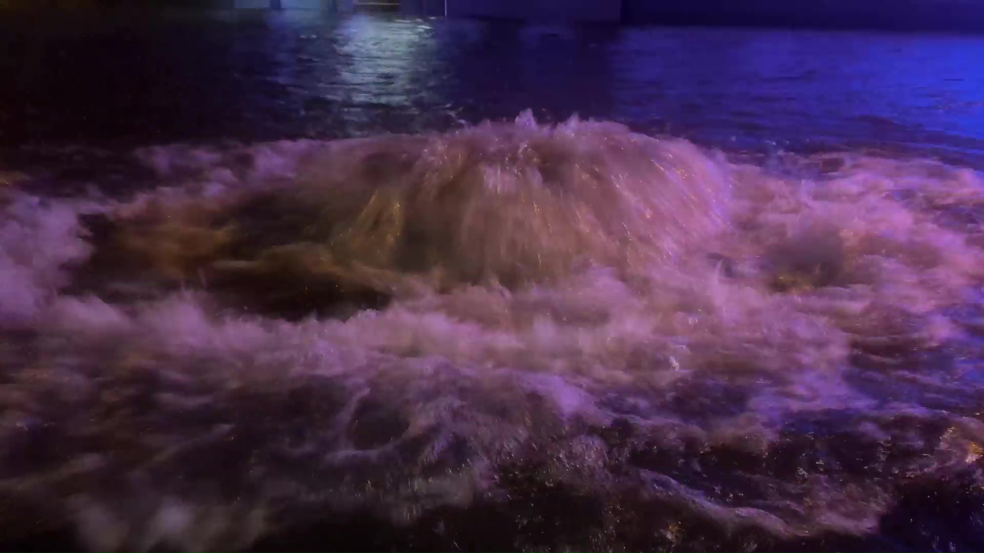 Sprudelndes Wasser strömt bei Nacht aus einem Kanal.