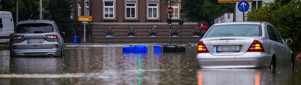 Überflutete Straße mit Autos und treibenden Mülltonnen in der Innenstadt. (c) dpa