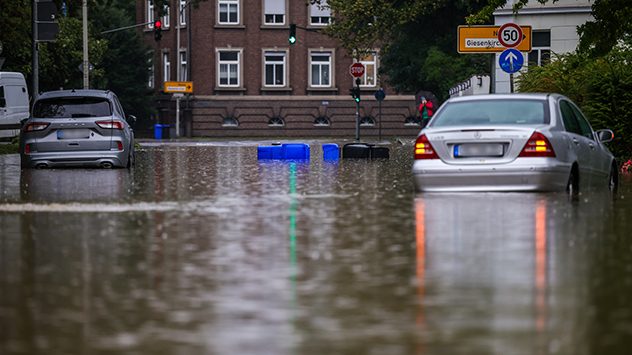 Überflutete Straße mit Autos und treibenden Mülltonnen in der Innenstadt. (c) dpa