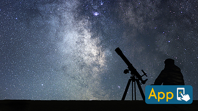 Silhouette of a person sitting beside a telescope on a tripod under a clear night sky filled with dense stars and the bright band of the Milky Way.