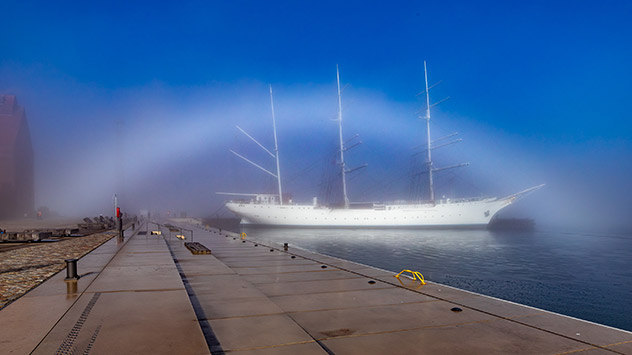 Nebelbogen vor blauem Himmel im Hafen von Stralsund