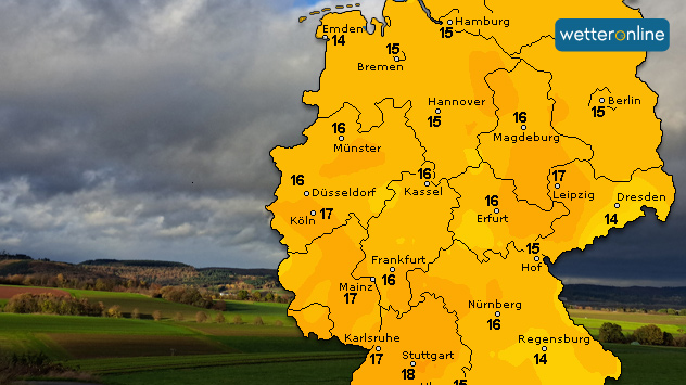 © Kathrin Wenzel Eine Deutschlandkarte zeigt Temperaturen zwischen 14 °C und 18 °C. Der Himmel im Hintergrund ist wolkig, teils mit Sonnenlicht über grünen Feldern.