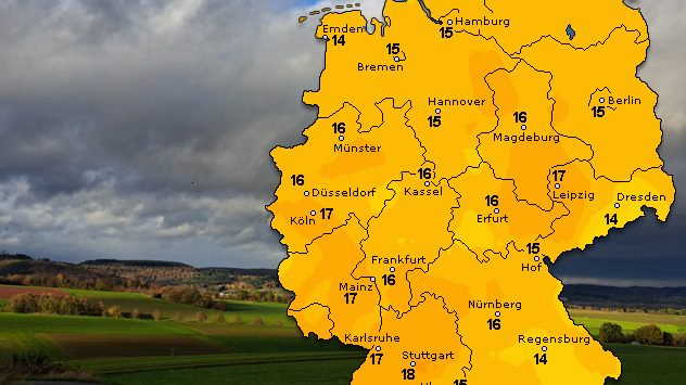 Eine Deutschlandkarte zeigt Temperaturen zwischen 14 °C und 18 °C. Der Himmel im Hintergrund ist wolkig, teils mit Sonnenlicht über grünen Feldern. (c) Kathrin Wenzel