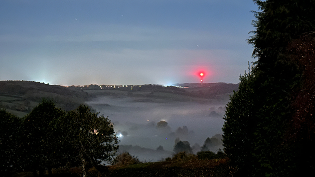 Evening view over Bledlow Ridge, Buckinghamshire showing dense fog settled in the valley under a clear sky, with a red tower light and distant village lights visible.