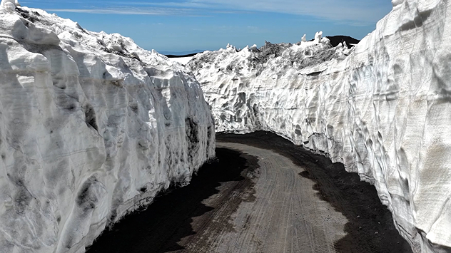 Links hoge sneeuwmuren langs een weg bij de Etna. Rechts een temperatuurkaart met een koud centrum bij de vulkaan. Duidelijke temperatuurdaling van west naar oost in de richting van de kust.