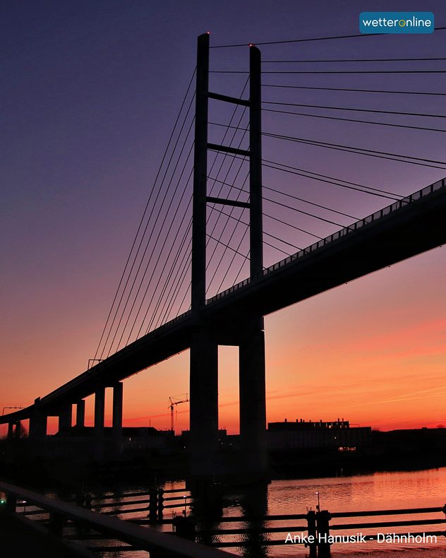 Das Bild zeigt eine Brücke über einen Fluss während der Dämmerung.