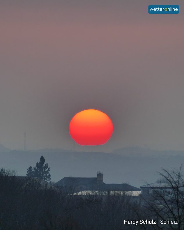 Das Bild zeigt eine knallrote Sonne am Horizont.