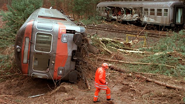 Ein Zug ist nach einem Sturm aus den Gleisen geraten und liegt auf der Seite, wÃ¤hrend umgestÃ¼rzte BÃ¤ume die Bahnstrecke blockieren. Eine Einsatzkraft in Warnkleidung begutachtet die SturmschÃ¤den â dramatische Folgen extremer Wetterlage. (c) dpa