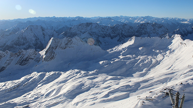 Verschneite Hochgebirgslandschaft rund um die Zugspitze mit weiten Schneeflächen und markanten Gipfeln bei klarem Winterwetter.