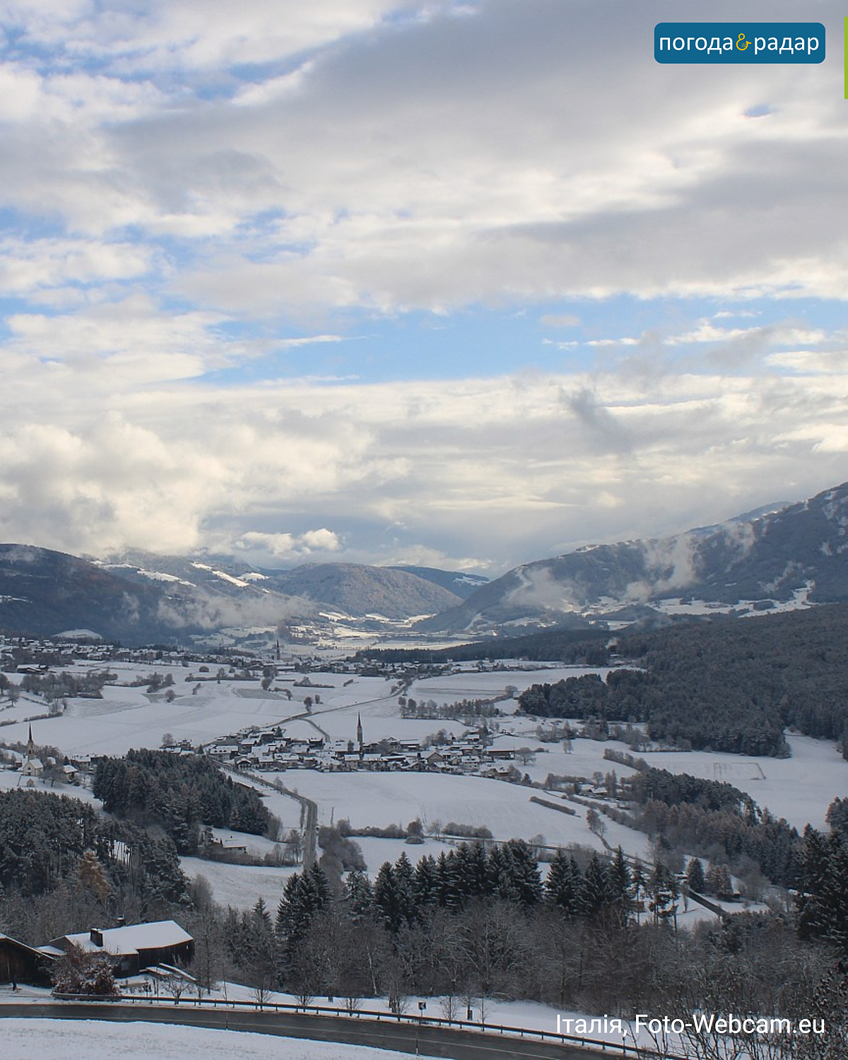 Засніжена долина в Південному Тіролі з селами і горами під частково хмарним небом.