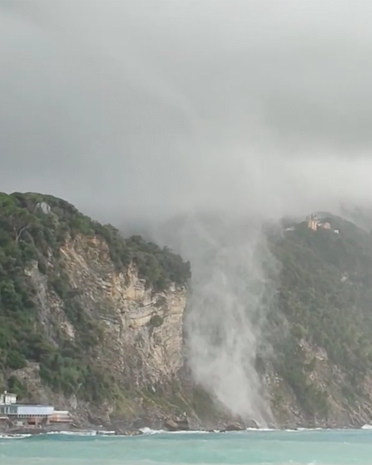 Tromba marina sul mare vicino alla costa sotto nuvole scure.
