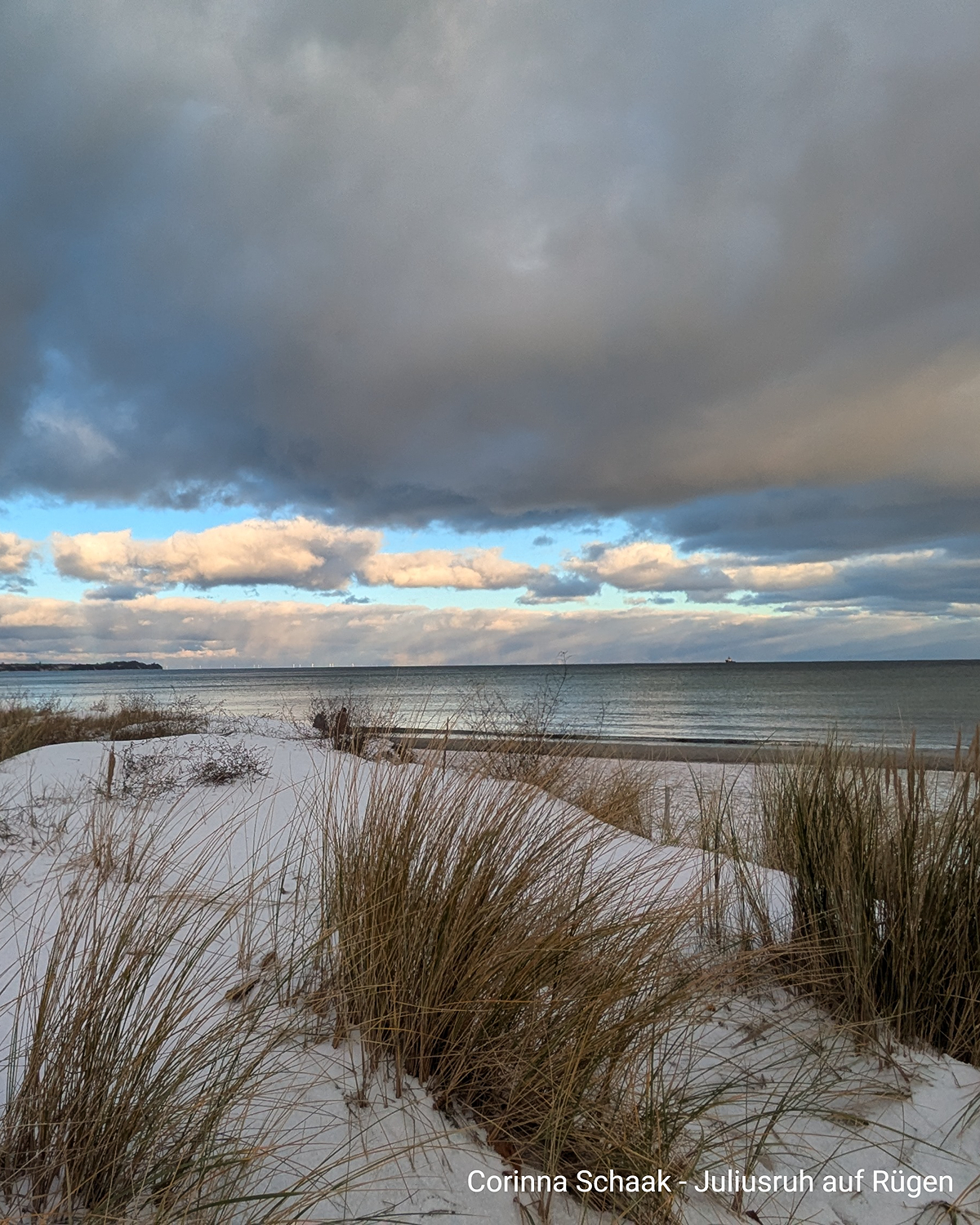 Verschneiter Strand auf Rügen mit Dünen, Meer und Wolkenhimmel