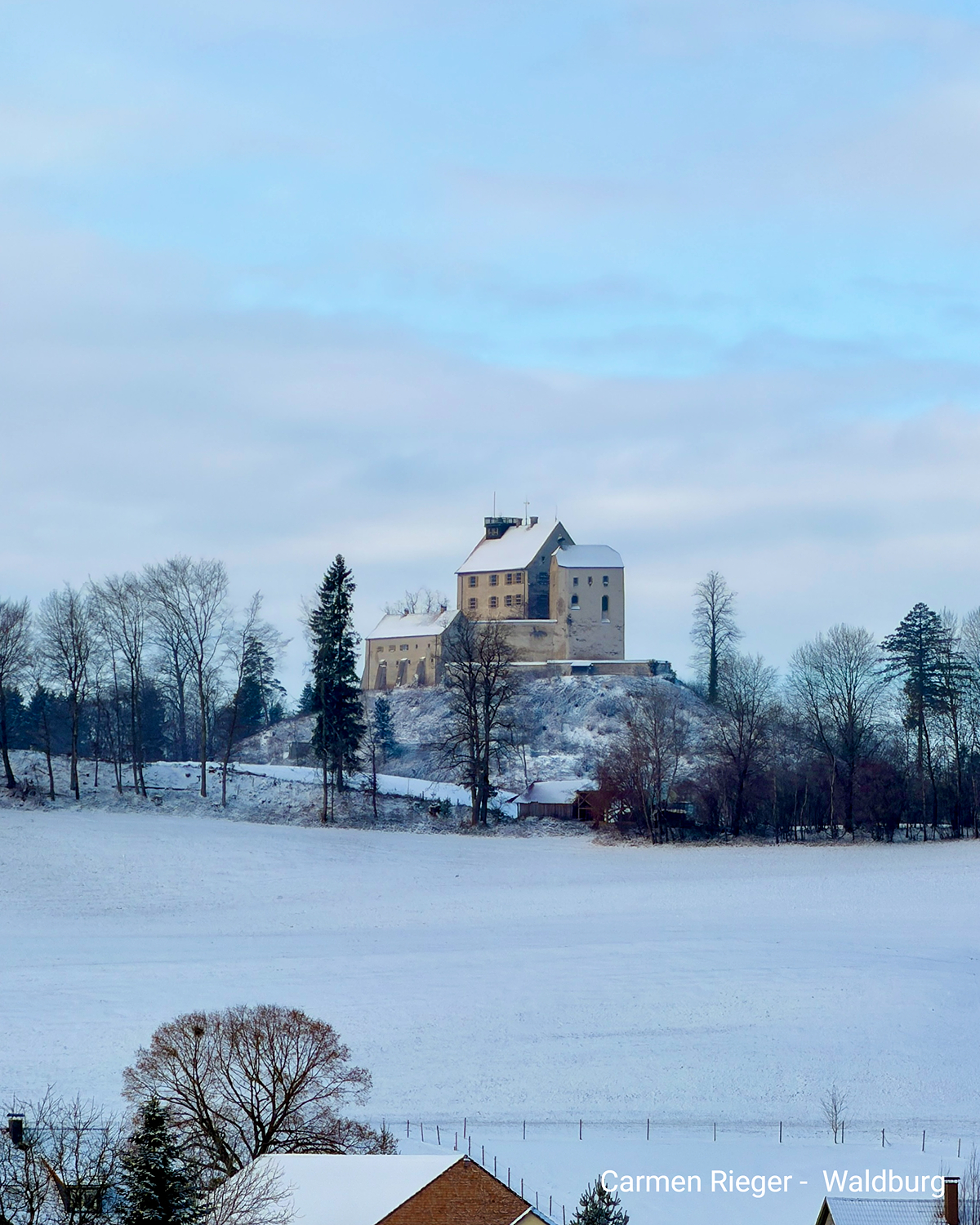 Schloss Waldburg auf verschneitem Hügel mit winterlicher Landschaft