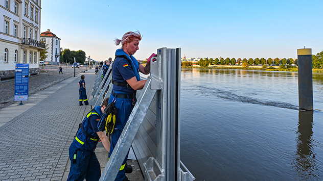 Helfer errichten eine mobile Hochwasserschutzwand an der Oder.