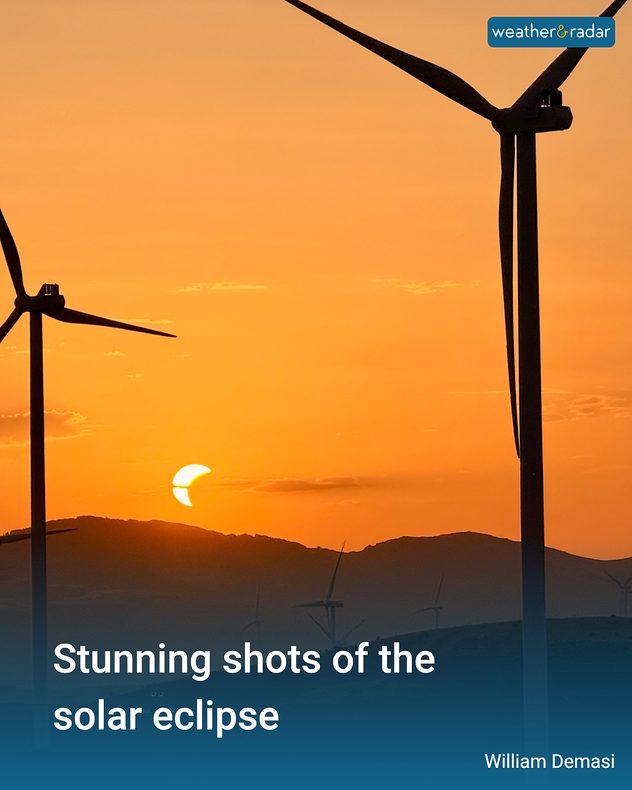 Partial solar eclipse setting over dark hills between silhouetted wind turbines in an orange sky, with text reading “Stunning shots of the solar eclipse” and “William Demasi.”