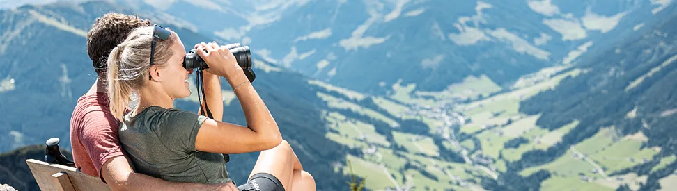 Ein Paar sitzt auf einer Bank und genießt die Aussicht auf die Bergkulisse.