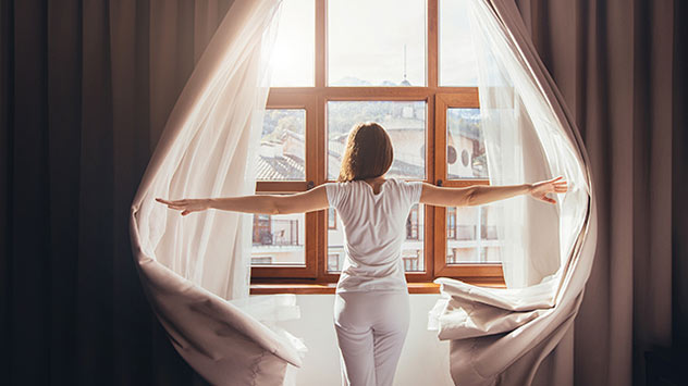 Frau schiebt Vorhänge bei Seite