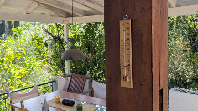 Thermometer im überdachten Gartenbereich und offizielle Wetterstation