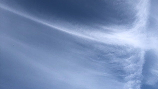 Thin, wispy cirrus clouds pictured with the blue sky seen behind and through them.