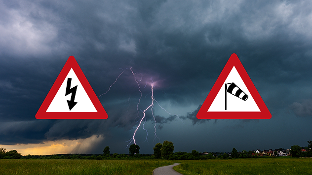 Lightning strikes beneath dark storm clouds over fields, with warning signs for thunderstorms and strong winds shown in foreground.
