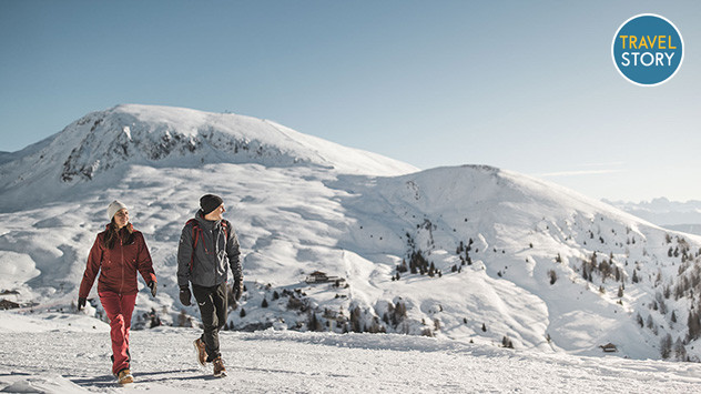 Ein Paar wandert durch die winterliche Berglandschaft. 