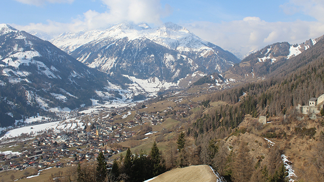 Das Webcambild zeigt ein Tal in den Alpen. Im Tal liegt noch Schnee, die Hänge sind hingegen grün.