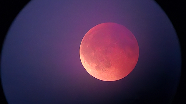 Red moon during an eclipse over Rieden on Lake Forggensee. The surface appears in reddish-purple shades.