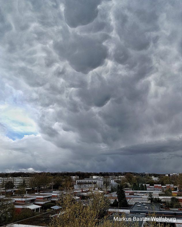 Dunkle, wulstige Wolken ziehen über eine Stadt hinweg. Die Wolken wirken bedrohlich und kündigen Schauer oder Gewitter aus Westen an.