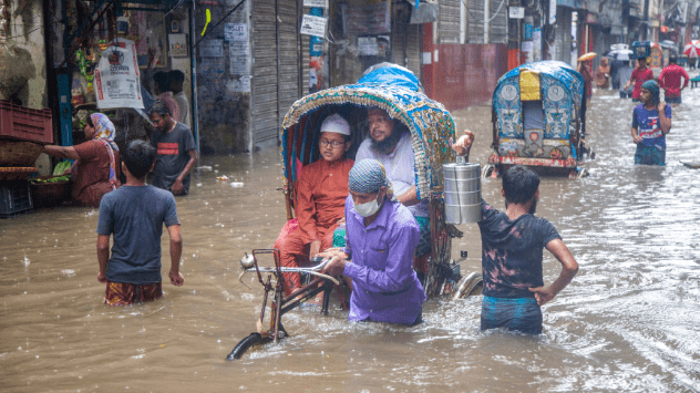Varias personas atraviesan una calle totalmente anegada en Bangladesh.
