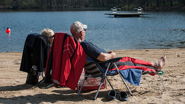 Frühlingswärme im März - älteres Paar sitzt am Flussufer in der warmen Sonne