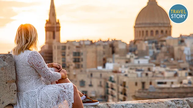 Eine Frau blickt in der Abenddämmerung auf die Stadt Valletta.