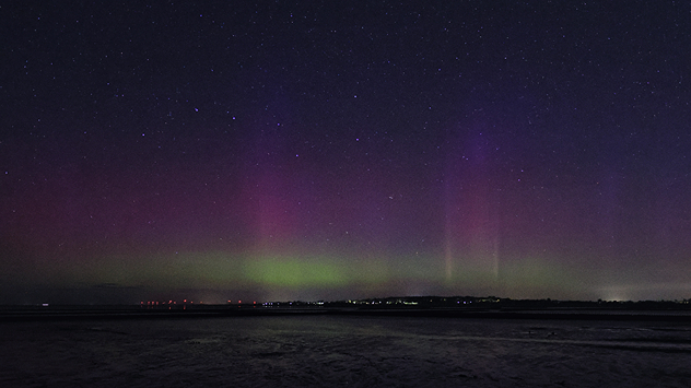 Polarlichter in Grün und Violett über Husum, Sternenhimmel und Wattlandschaft im Vordergrund