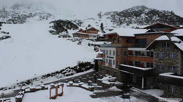 Verschneites Bergdorf mit Hotel und Chalets in nebliger Winterstimmung.