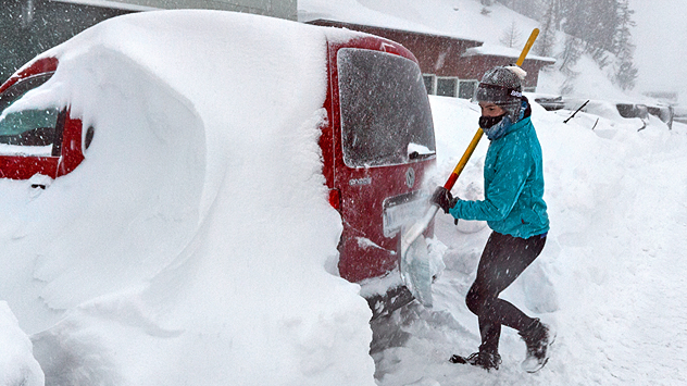 Une personne déneige sa voiture.
