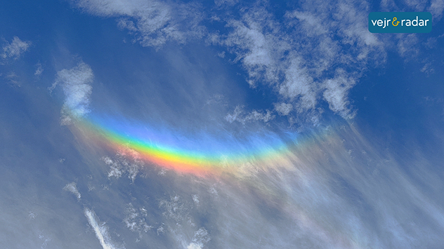 Farverig omvendt regnbue på himlen mellem skyer i klart vejr.