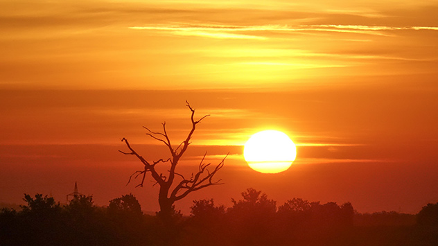 Die aufgehende Sonne färbt den Himmel tiefrot.