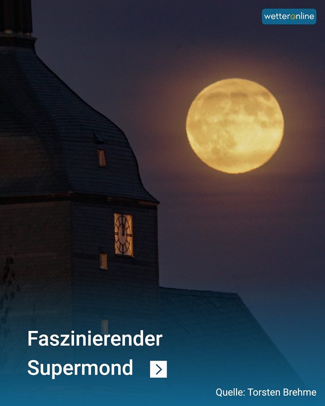 Vollmond über einem Kirchturm im dunklen Abendhimmel.