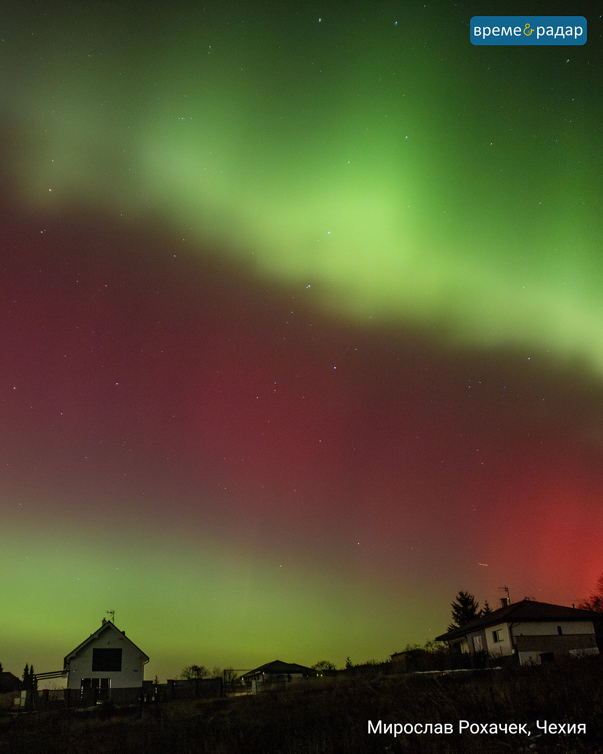 Зелено-червено северно сияние над къщи през нощта. Жилищен район в Чехия.