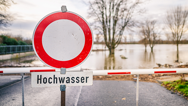 Schild Straßensperrung bei Hochwasser an einem Fluss