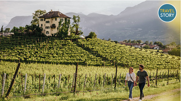Ein Paar wandert entlang eines Weinbergs an der Südtiroler Weinstraße. 