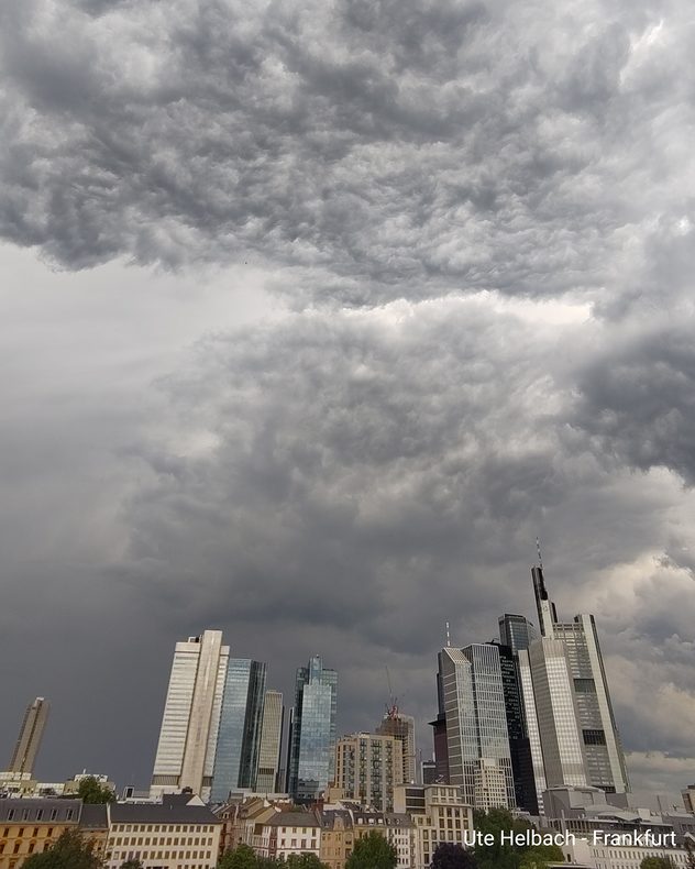 Frankfurter Skyline unter einer dunklen und stark strukturierten Gewitterwolke. Hochhäuser ragen vor dem bedrohlichen Himmel auf.